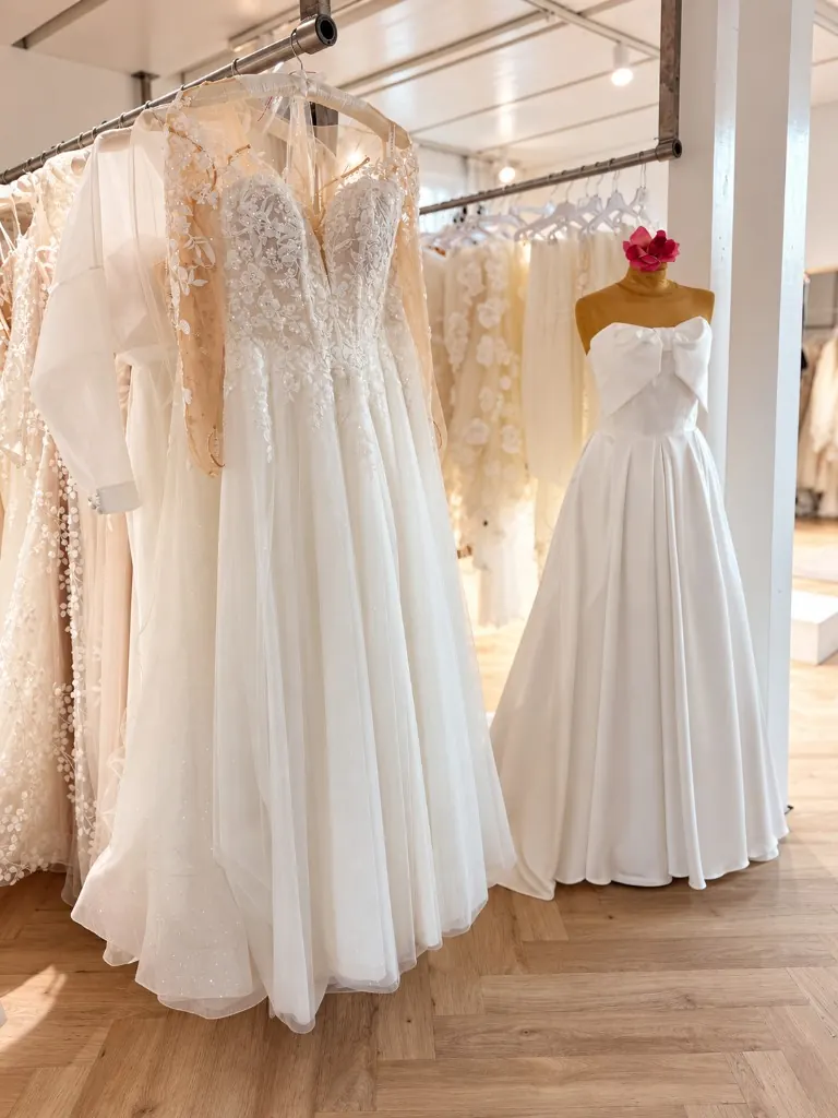 Brautkleider an der Stange und Mannequin mit Schleifen-Kleid im hellen Showroom La vera sposa Köngen (Mit KI bearbeitet)