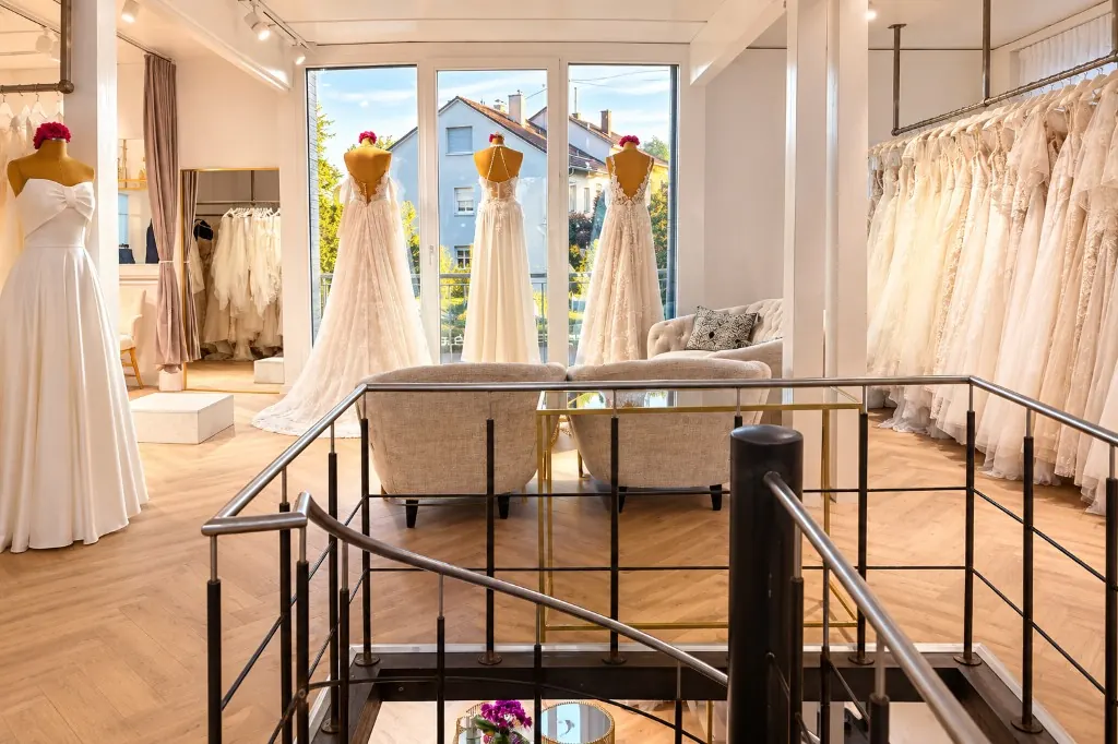 Blick von der Treppe in den Showroom La vera sposa Köngen mit Sitzecke, Kleiderstangen und Schaufenster (Mit KI bearbeitet)